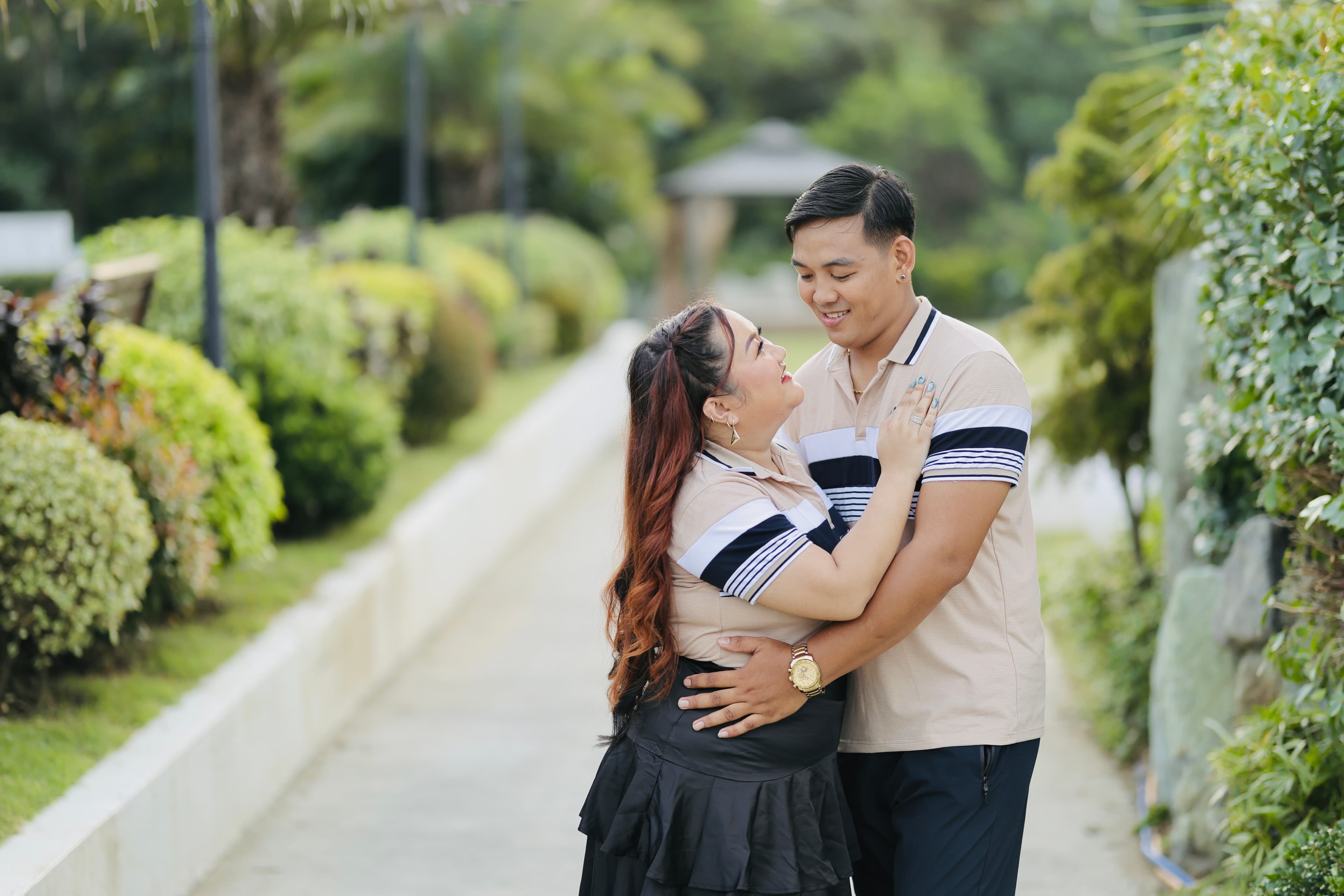 Mayumi and Mardy smiling at each other in a garden embrace